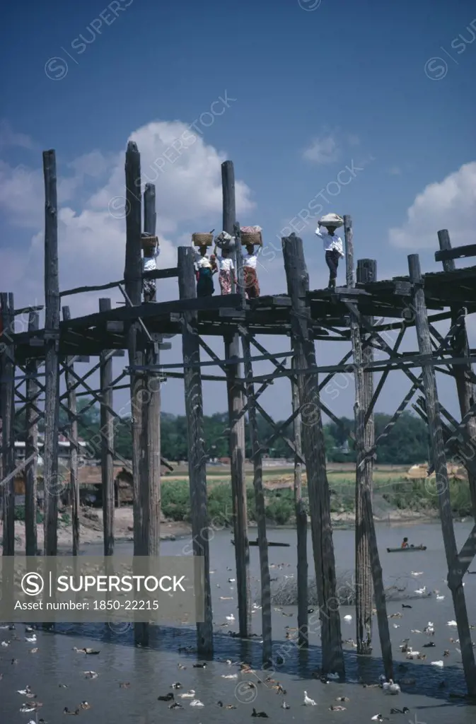 Thailand, North, Bridges, Women Carrying Baskets On Their Heads Crossing High Wooden Bridge Across River And Ducks.