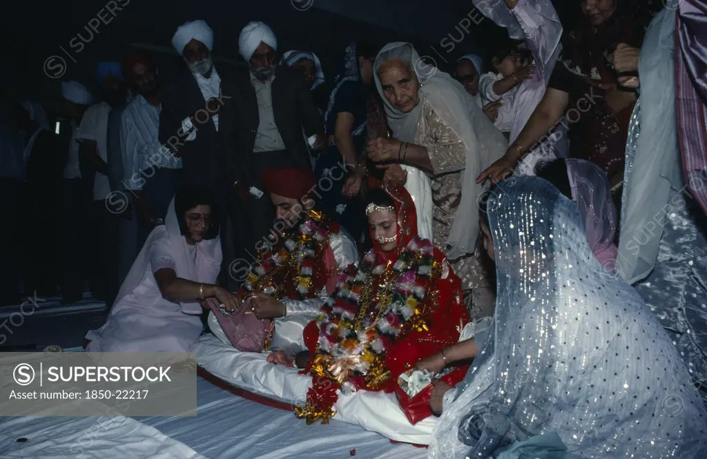 England, Religion, Sikhism, Bride And Groom Receiving Gifts Of Money From Guests During Wedding Ceremony.
