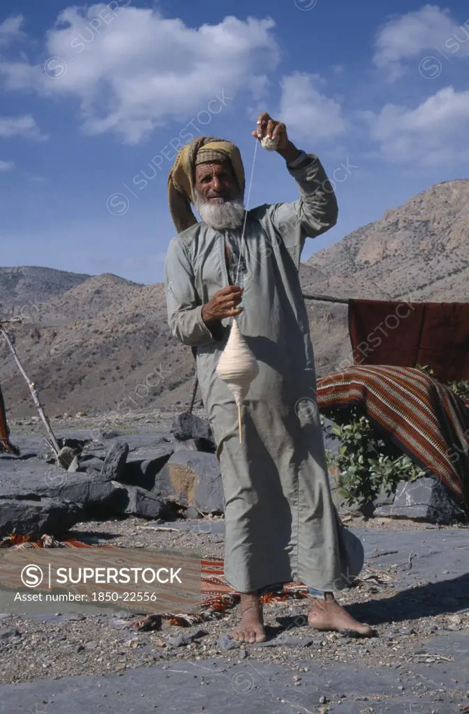 Uae, Oman, Jabal Shams, Elderly Man Using Spindle To Spin Thread For Rug Making.