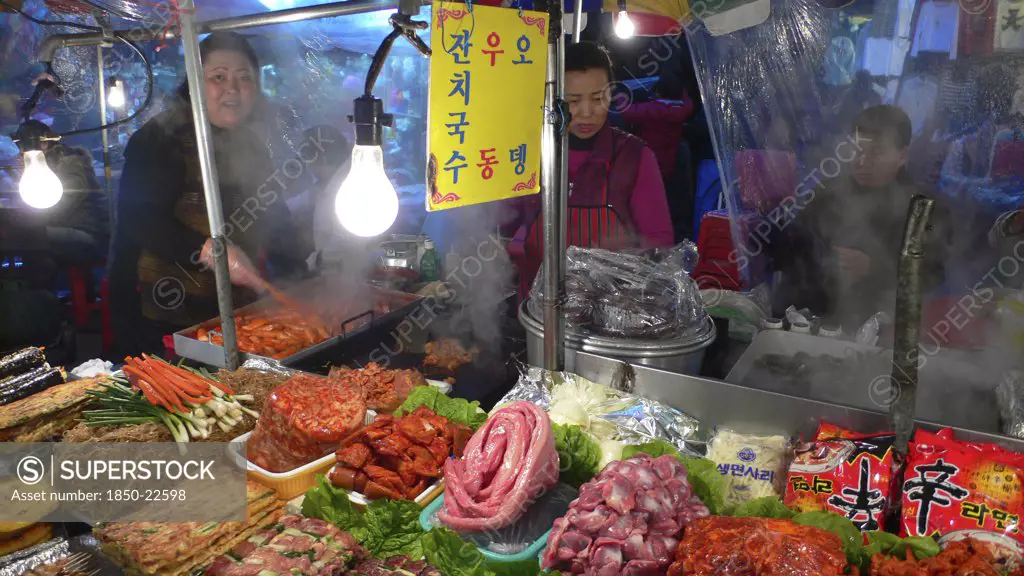 Korea, South, Seoul, 'Namdaemun - Namdaemun Market, December Evening, Food Stall, Women Cooking, Customers Eating, Stacks Of Meat And Fish Waiting To Be Cooked'