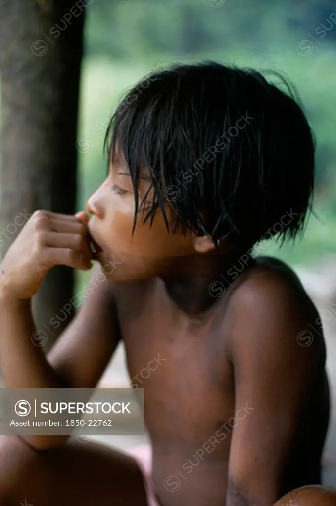 Colombia, Choco, Embera Indigenous People, 'Portrait Of Embera Boy With Typical Fringe Haircut Sitting At Entrance To Stilted Family Home. Faint Body Decoration Marks From Purple/Black Dye Extracted From Jagua Fruit, Still Visible Ten Days After Ceremony. Pacific Coastal Region Tribe.  Pacific Coastal Region Tribe 10 American Children Colombian Columbia Hispanic Immature Indegent Kids Latin America Latino One Individual Solo Lone Solitary South America Single Unitary Young Unripe Unripened Green