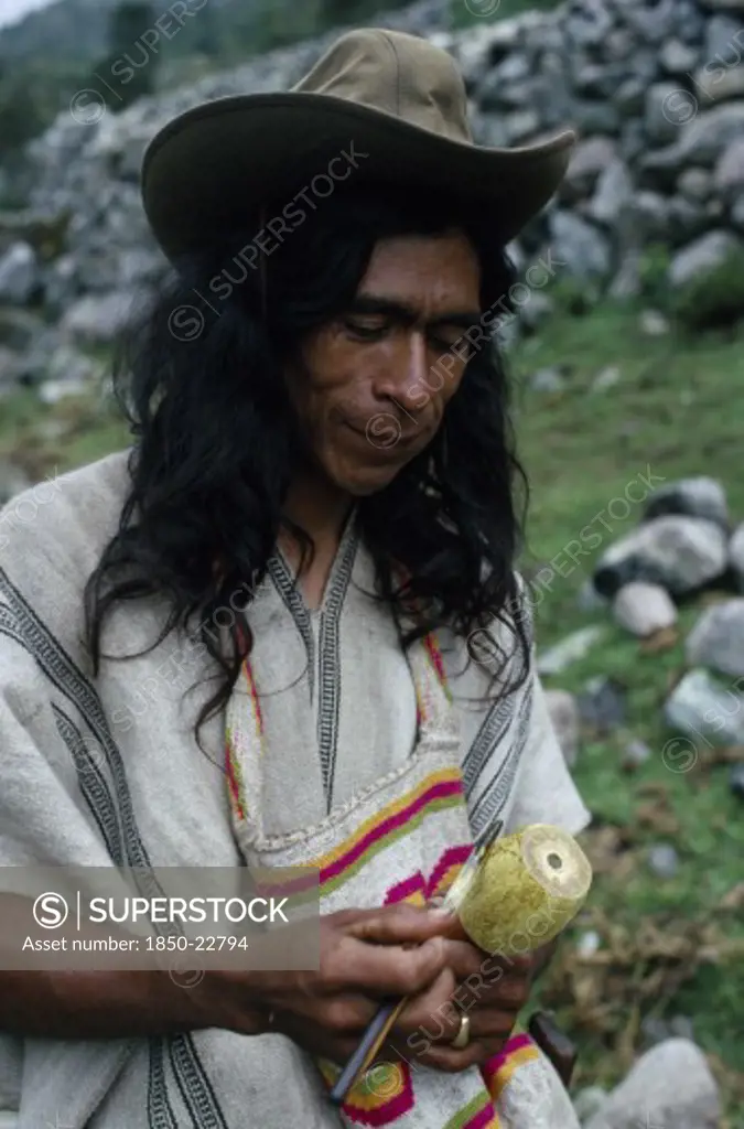 Colombia, Sierra Nevada De Santa Marta, Ika, Ika Man In Traditional Dress With Hand Woven Mochila Shoulder Bag And Holding Poporo A Small Gourd Containing Finely Powdered Lime From Burnt Sea Shells.He Sticks The The Lime Into A Wad Of Coca Leaves Held In The Cheek.Lime Acts As Catalyst To Release The Cocaine Alkaloid From The Chewed Leaves.  Arhuaco Aruaco Indigenous Tribe American Classic Classical Colombian Colombia Hispanic Historical Indegent Latin America Latino Male Men Guy Older South Ame