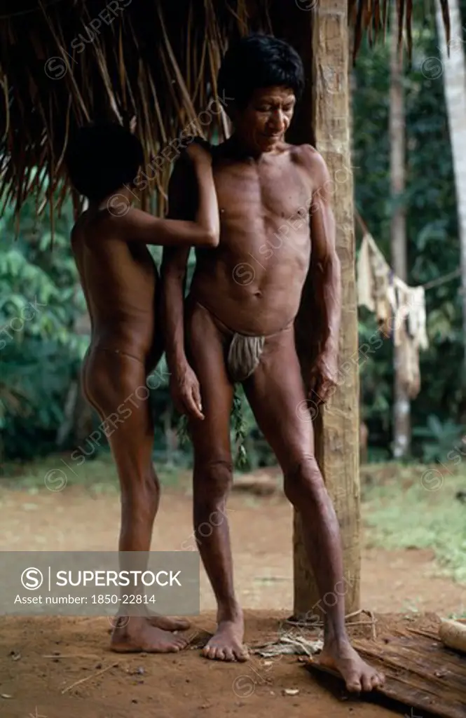Colombia, North West Amazon, Vaupes, Middle Aged Maku Nomad Standing With His Son Beside Frame Of Thatched Home At Base Village.  Indigenous Tribe Indian Nomadic American Colombian Columbia Hispanic Indegent Kids Latin America Latino Male Men Guy South America Vaupes Male Man Guy Vaupes
