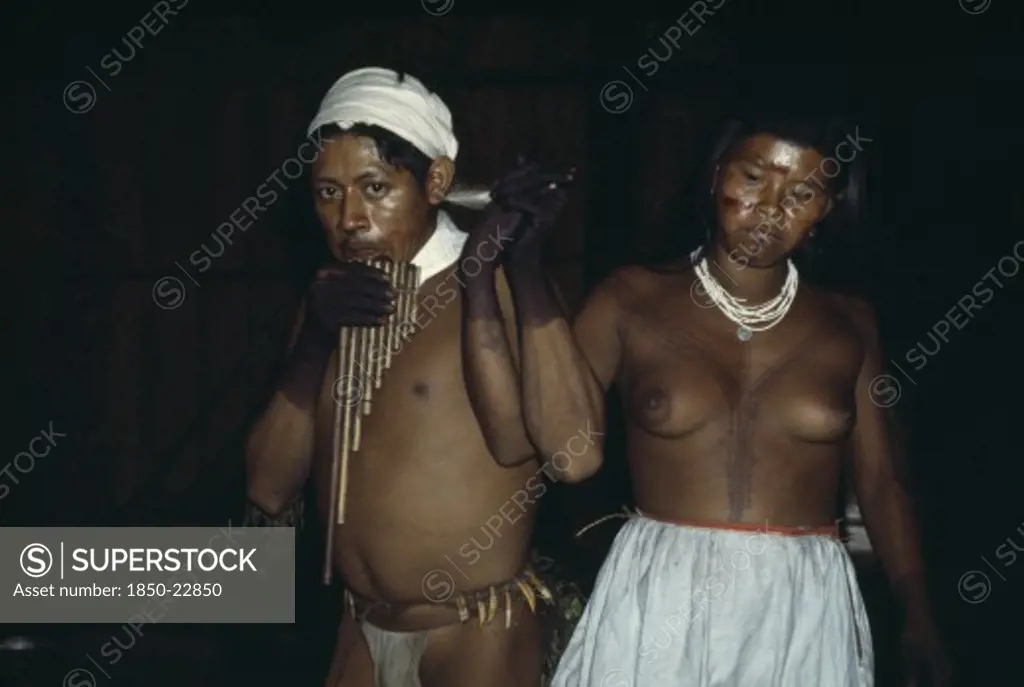 Colombia, North West Amazon, Tukano Indigenous People, Group Of Young Barasana Dancing A Panpipe Dance Inside Maloca/Communal Home - Their Bodies And Faces Painted With Red Achiote For Ceremonial Manioc Festival. Tukano Sedentary Indian Tribe North Western Amazonia American Colombian Columbia Female Women Girl Lady Hispanic Indegent Latin America Latino South America Tukano Female Woman Girl Lady Immature