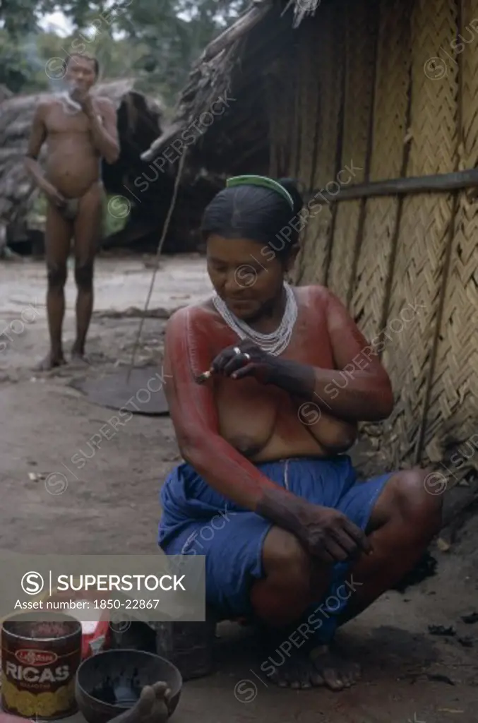 Colombia, North West Amazon, Tukano Indigenous People, Barasana Woman Paulina  Applying Red Achiote Fruit Body Paint To Arms And Upper Body In Preparation For Manioc Festival.  Hands Already Coloured Dark Purple To Wrists With We Dye From Boiled Leaves.  Tukano Sedentary Indian Tribe North Western Amazonia Body Decoration American Colombian Columbia Female Women Girl Lady Hispanic Indegent Latin America Latino South America Tukano