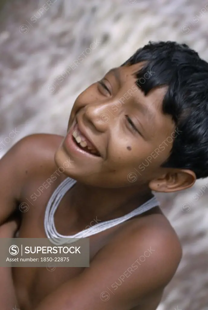 Colombia, North West Amazon, Tukano Indigenous People, Head And Shoulders Portrait Of Laughing Barasana Boy Wearing Multi-Strand White Glass Bead Necklace.Tukano Sedentary Indian Tribe North Western Amazonia American Colombian Columbia Hispanic Indegent Kids Latin America Latino South America Tukano
