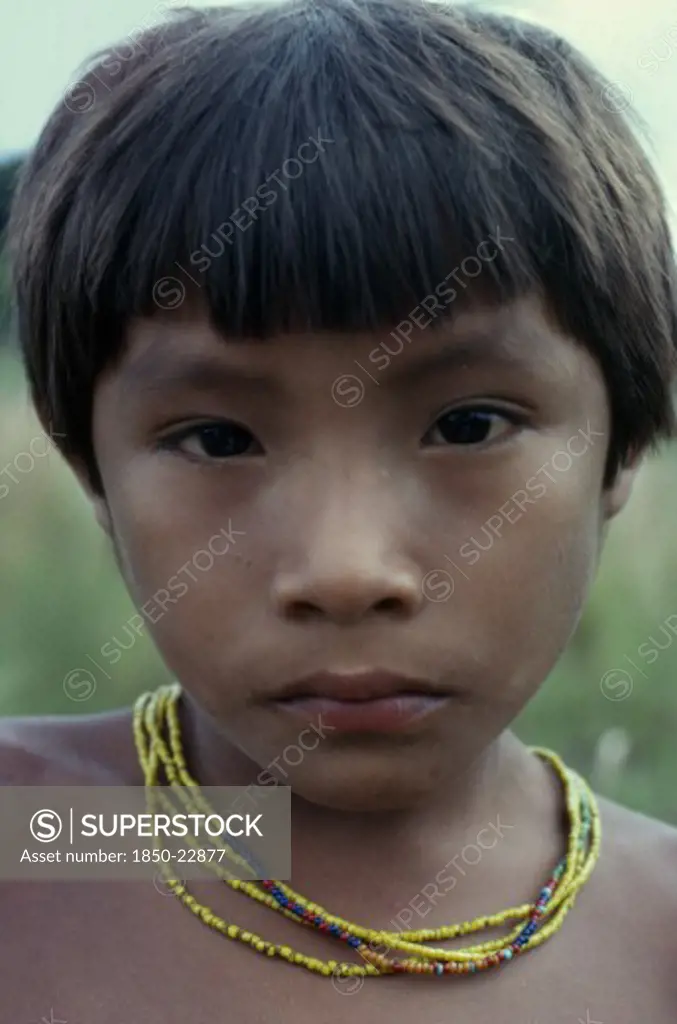 Colombia, North West Amazon, Tukano Indigenous People, Head And Shoulders Portrait Of Young Barasana Boy Looking Direct To Camera  Wearing Multi-Strand Coloured Bead Necklace. Tukano Sedentary Indian Tribe North Western Amazonia