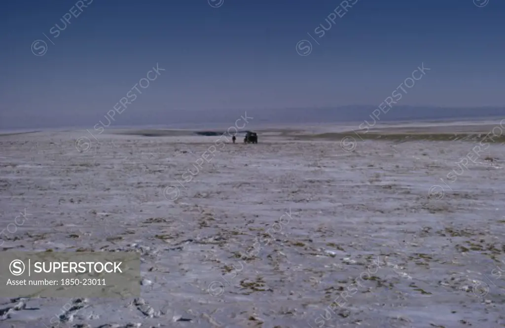 Mongolia, Gobi Desert, Mid-Winter On The Edge Of The Gobi With A Distant Russian Gaz Jeep And Lone Figure Walking In Barren Frozen Landscape