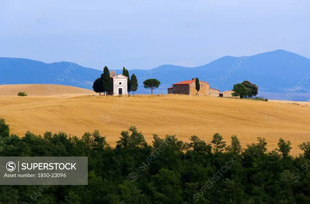 Italy, Tuscany, San Quirico DOrcia, Chapel And Farmhouse Set Amongst Wheatfields On The Top Of A Hill In The Val D'Orcia