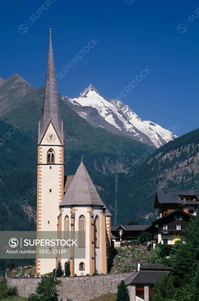 Austria, Hohe Tauern, Karnten, 'High Tauern National Park, Heiligenblut.  Parish Church Of St Vincent With Snow Capped Grossglockner Peak Behind.'