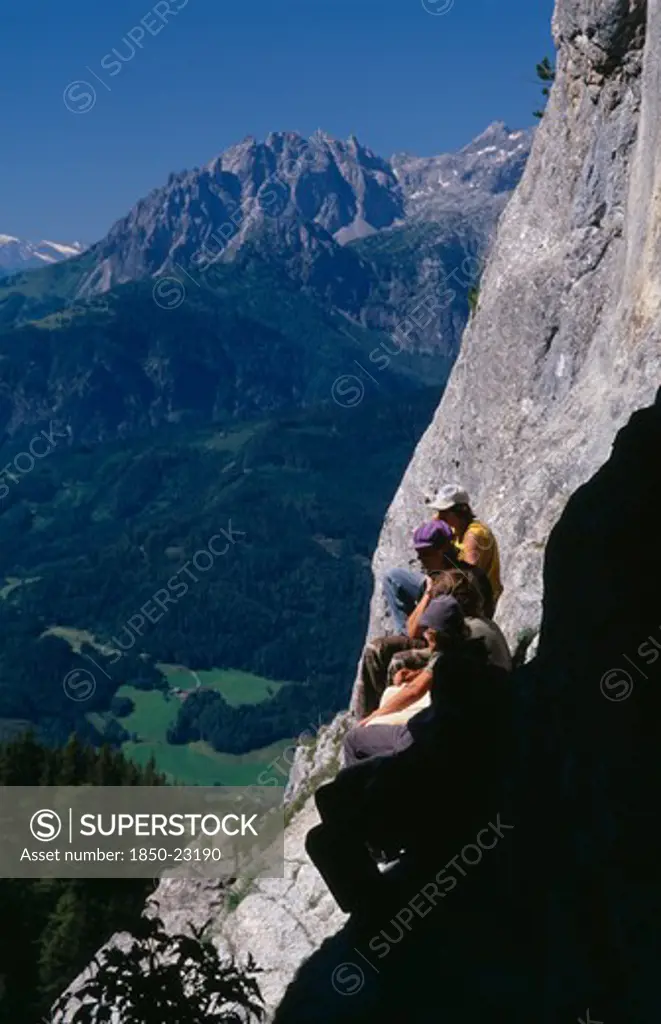 Austria, Salzburg, Eisriesenwelt, 'Group Of Hikers At Cave Entrance Near Werfen Looking Out Over Green, Wooded Slopes Of Valley Below.'