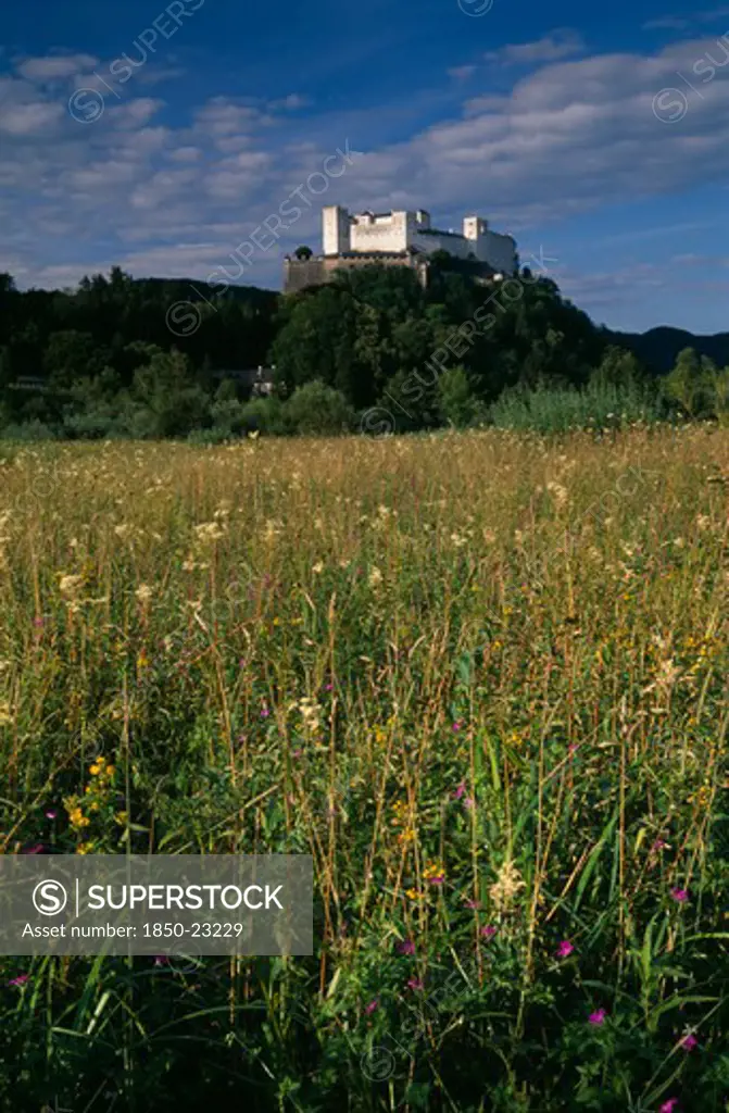 Austria, Salzburg, Hohensalzburg Fortress Situated On Densely Forested Hillside Above Meadowland.  Constructed In 1077 By Archbishop Gebhard.