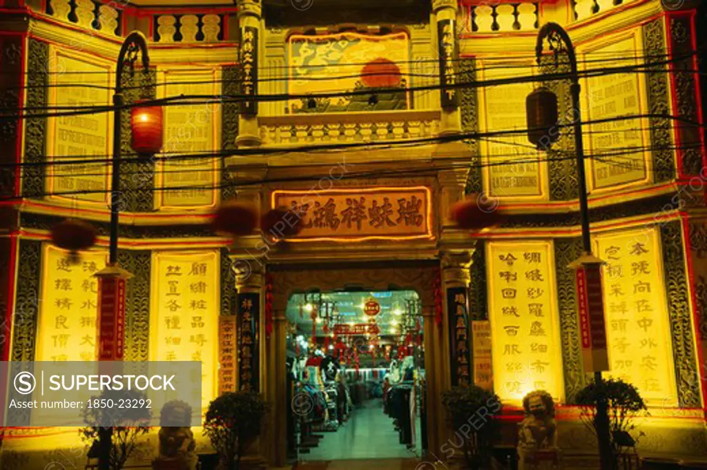 China, Beijing, 'Silk Emporium On Dazhalan Jie, Exterior Facade Illuminated At Night With Open Entrance And View Inside Over Shop Floor.'