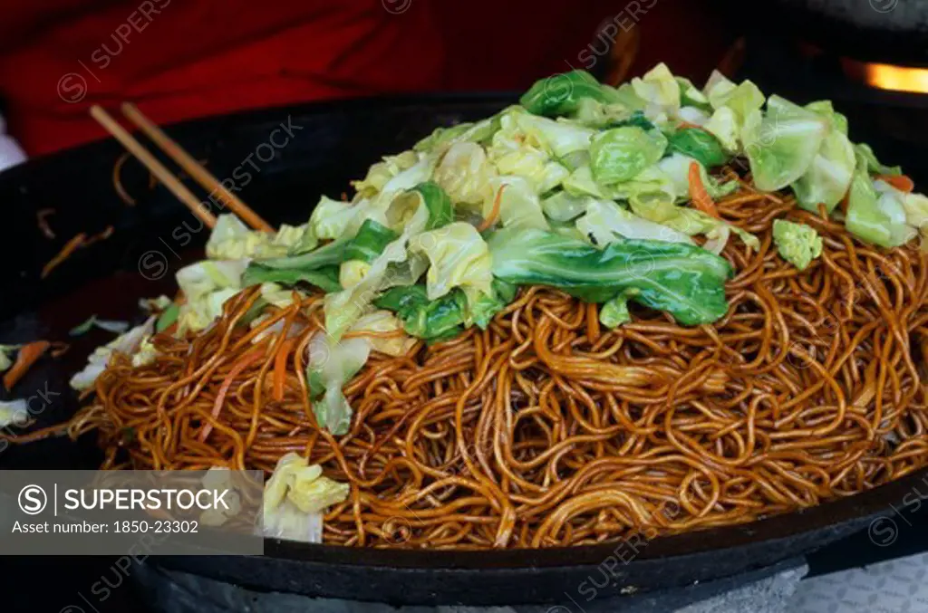 China, Beijing, Donghua Yeshi Food Market.  Noodles And Pak Choi In Wok.