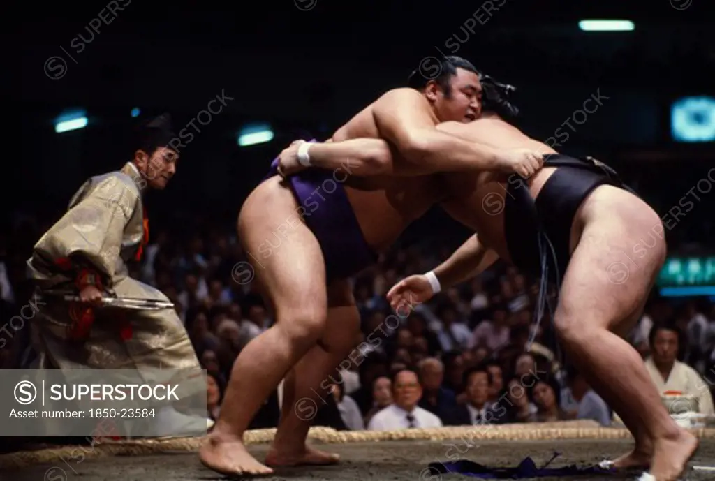 Japan, Samurai, Sumo, 'Sumo Wrestlers In Ring Watched By Referee Wearing The Costume Of A Shogun.  Sumo Is An Ancient Form Of Wrestling Thought To Have Originated In Japan Some 2,000 Years Ago.  The Ring Consists Of A Circle Of Clay Set On A Square Mound And A Bout Is Decided When Any Part Of A WrestlerS Body Except The Soles Of His Feet Touches The Ground Or If He Is Pushed From The Ring.'