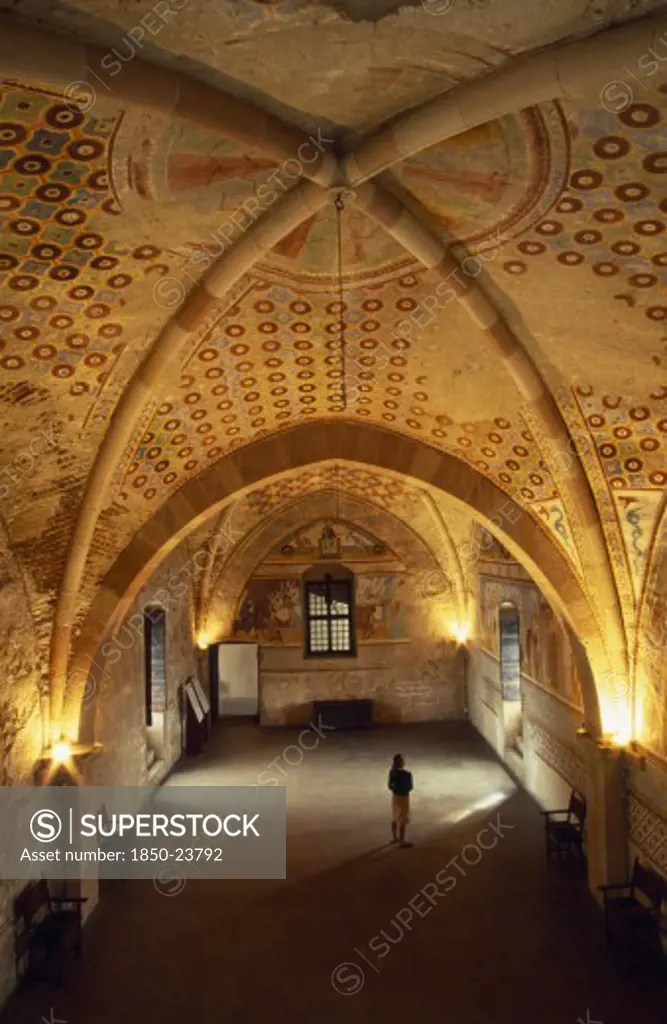Italy, Lombardy, Lake Maggiore, Angera.  Interior Of Reception Hall In Rocca Di Angera Medieval Castle With Painted Vaulted Ceiling And Fresco Wall Decoration.  Female Visitor Looking Up At Paintings.