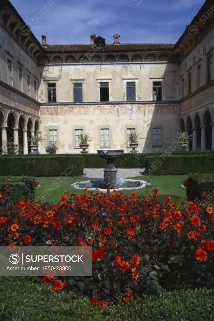 Italy, Lombardy, Bisuschio, Villa Cicogna Mozzoni East Of Lake Maggiore.  Exterior Of Renaissance Villa Built Between 1400 -1500 By The Mozzoni Family.  Water Feature And Dahlias In Foreground.