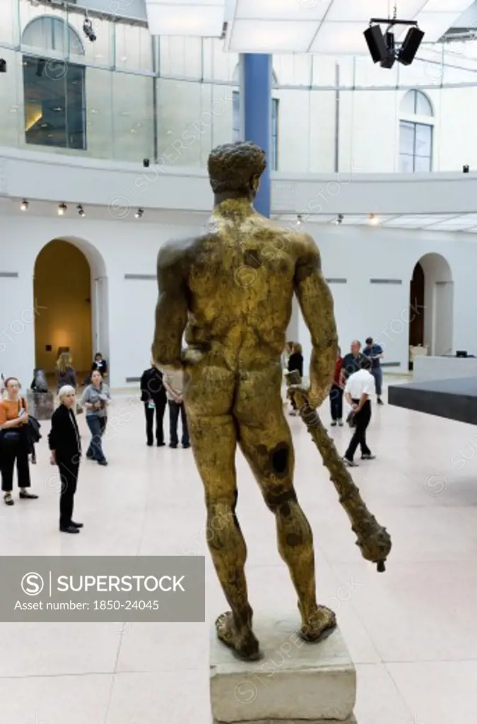 Italy, Lazio, Rome, The Capitoline Museum Palazzo Dei Conservatori. Visitors View The 2Nd Century Bc Gilded Bronze Statue Of Hercules In The Portico Of Marcus Aurelius