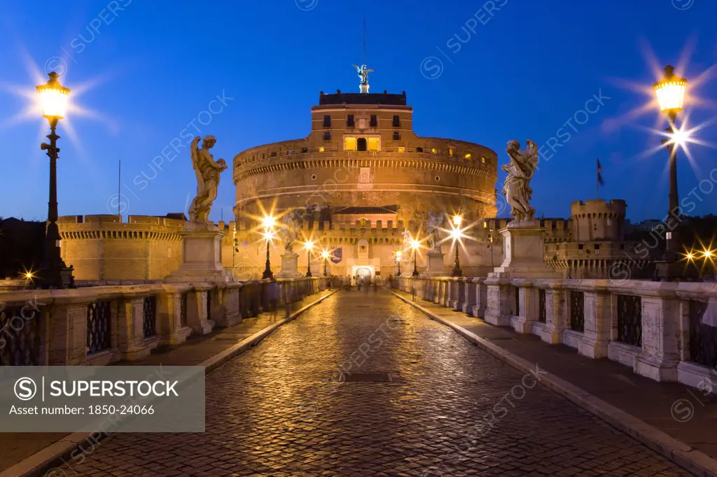 Italy, Lazio, Rome, The 3Rd Century Bridge Ponte Sant'Angelo Lined With Statues And The 13Th Century Castle Of Castel Sant'Angelo On The Banks Of The Riber Tiber Illuminated At Dusk. Originally The Mausoleum Of Emperor Hadrian It Became The Residence Of Popes In Times Of Unrest Linked To The Vatican By A Viaduct