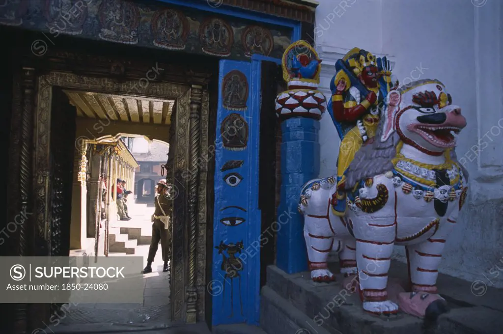 Nepal, Kathmandu, Dubar Square. Royal Palace Or Hanuman Dhoka. Statue Of Shakti Riding A Lion Next To Private Entrance To Palace With A Guard Seen Through Doorway