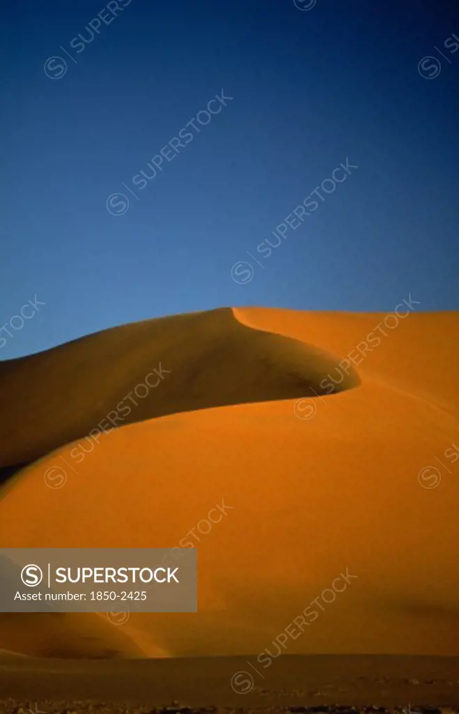 Libya , South West, Achan , Orange Desert Sand Dune Against A Clear Blue Sky