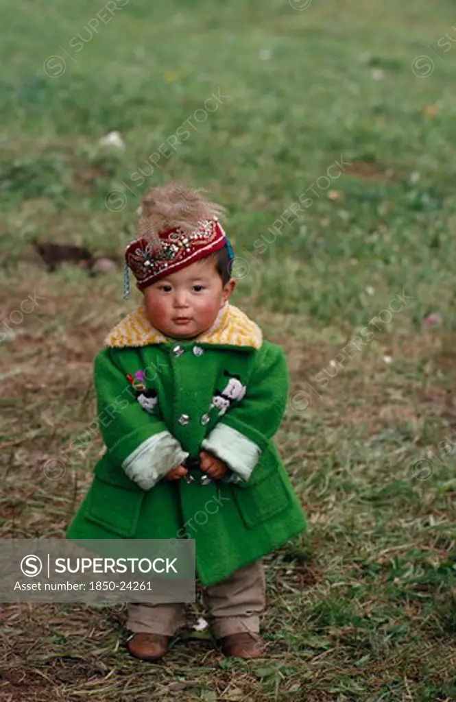 China, Children, Portrait Of Young Kazakh Child Wearing Green Wool Coat And Embroidered Cap.