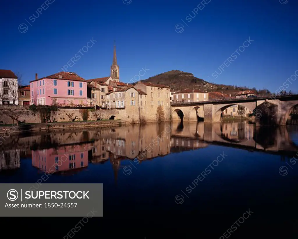 France, Midi-Pyrenees, Aveyron, 'Saint-Antonin-Noble.  Village Houses, Church Spire And Bridge Reflected In Water Of The River Aveyron.'