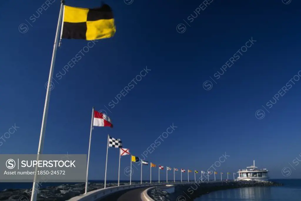 Uae, Dubai, Jumeirah Beach.  Curving Marina Wall And Line Of Flags.