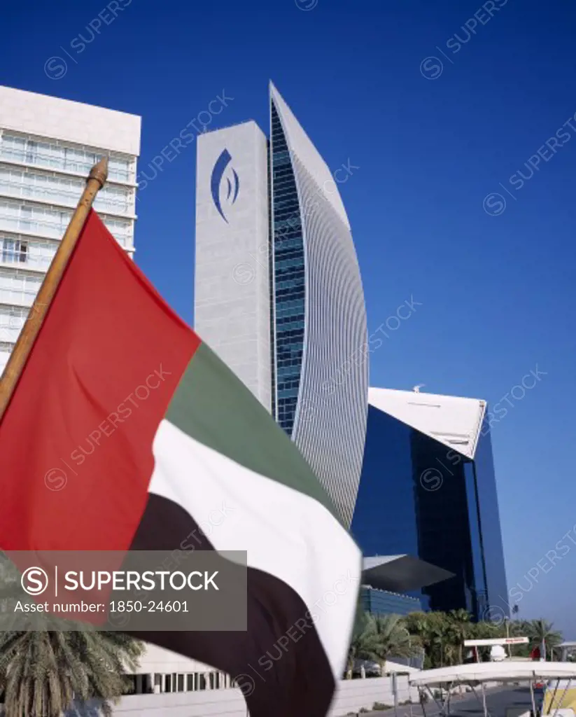 Uae, Dubai, National Bank Of Dubai Seen From Dhow On Dubai Creek With Uae Flag In The Foreground.