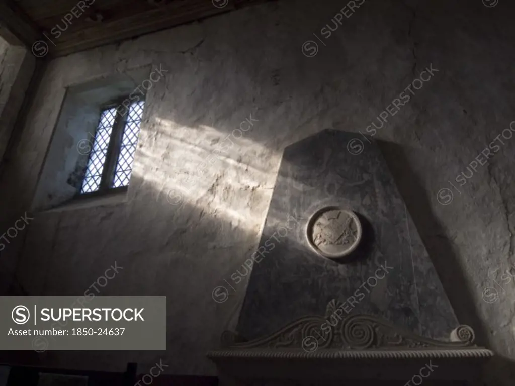 England, West Sussex, Boxgrove, Boxgrove Priory Church Of St Mary And St Blaise. Interior View Of  Light Shining Through Small Window Onto A Wall And Marble Monument.