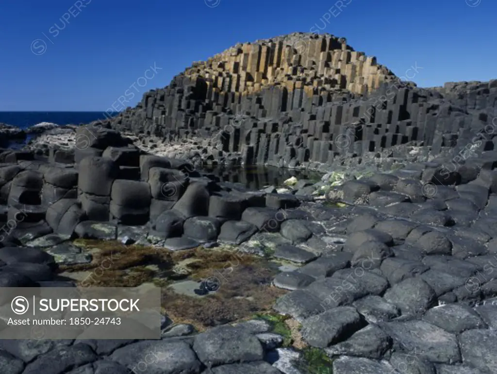 Northern Ireland, County Antrim, Giants Causeway, Interlocking Basalt Stone Columns Left By Volcanic Eruptions. View Across The Main And Most Visited Section Of The Causeway With The Coastline Seen Behind.