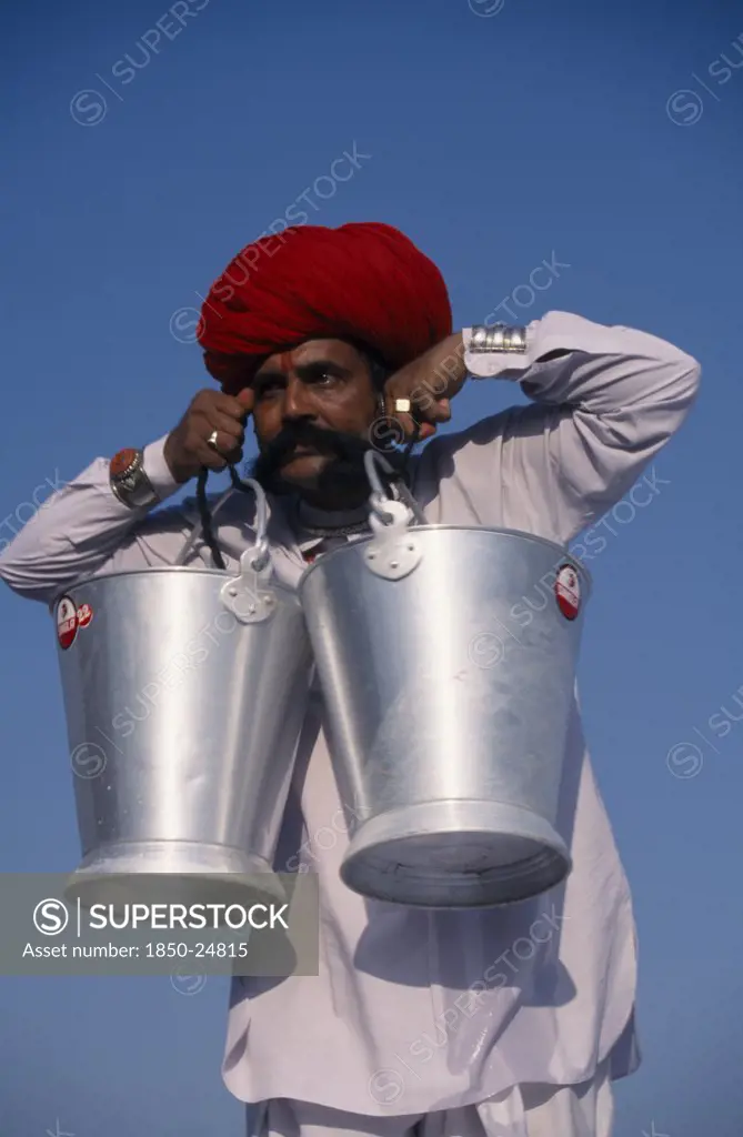India, Rajasthan, Bikaner, Rajput Man Lifting Buckets Of Water With His Moustache During The Camel Festival.