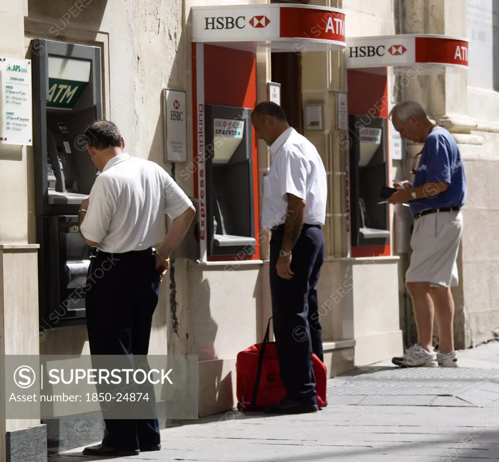 Malta, Valletta, Three Men Using Separate Atm Cash Machines On Republic Street
