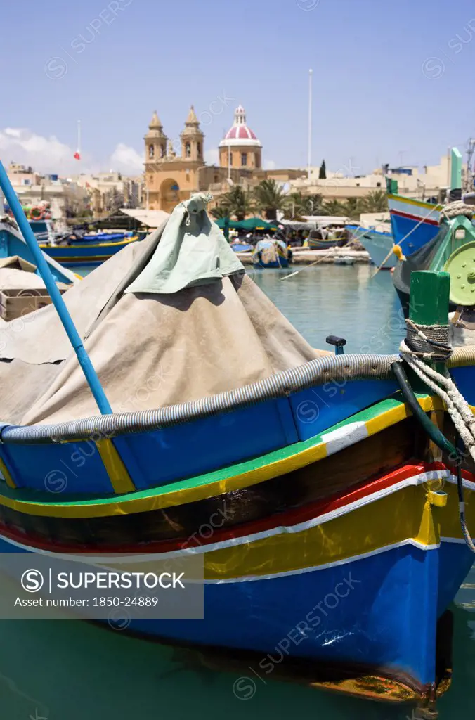 Malta, Marsaxlokk , Fishing Village Harbour On The South Coast With Colourful Kajjiki Fishing Boats And The Church Dedicated To Our Lady Of The Rosary The Madonna Of Pompeii