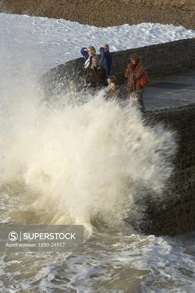 England, East Sussex, Brighton, Waves Crashing Onto Beach And Groyne With People Getting Wet.