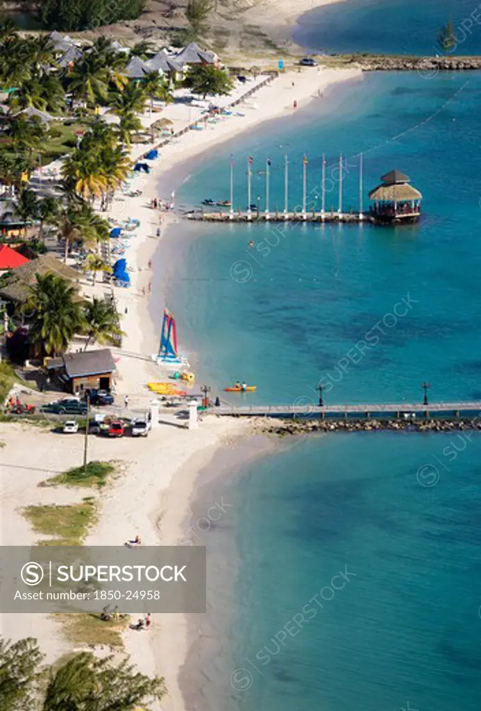 West Indies, St Lucia, Gros Islet , 'The Coconut Palm Tree Lined Beach At Sandals Grande St Lucian Spa And Beach Resort Hotel With Tourists Walking, Swimming Or Sunbathing'