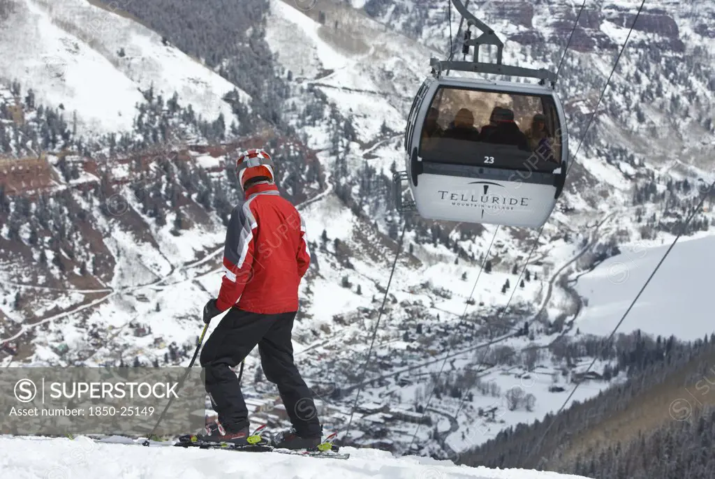 Usa, Colorado, Telluride, Skier On Slopes With Cable Car Ski Lift Overhead Passing By.