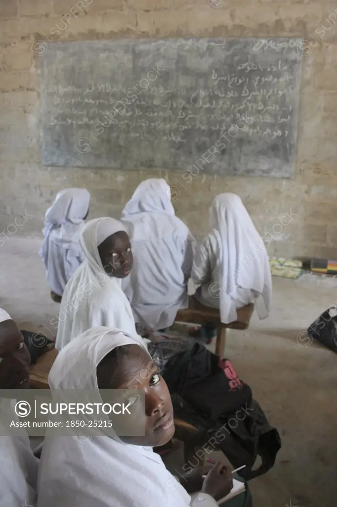 Gambia, Western Gambia, Tanji, Tanji Village.  African Muslim Girls Wearing White Headscarves Attending A Class At The Ousman Bun Afan Islamic School.  Girls In Foreground Looking Back Towards The Camera.