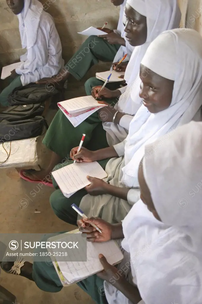 Gambia, Western Gambia, Tanji, 'Tanji Village.  African Muslim Girls Wearing White Headscarves While Attending A Class At The Ousman Bun Afan Islamic School, Sitting In Line Writing In Exercise Books.'