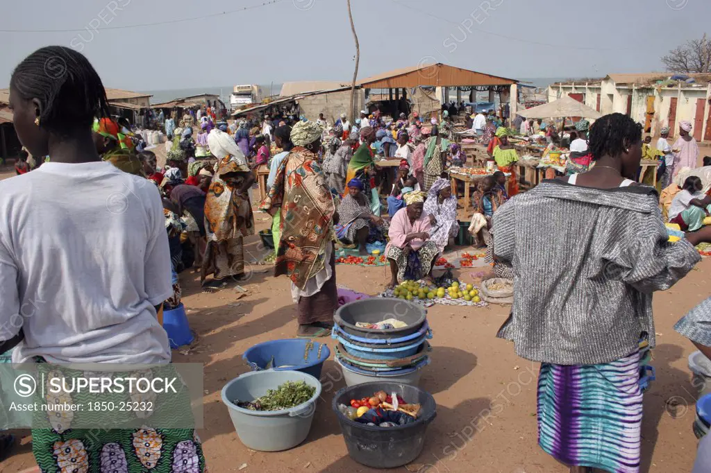 Gambia, Western Gambia, Tanji, Busy Market Scene With Women Selling Fruit And Vegetables And Coloufully Dressed Crowd.