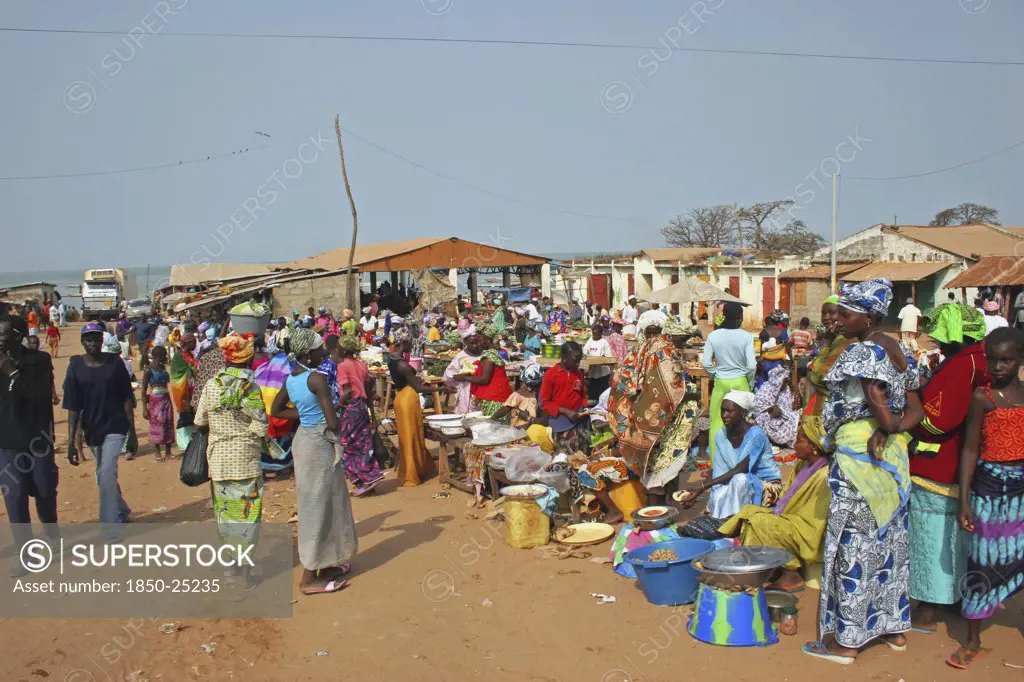 Gambia, Western Gambia , Tanji, Tanji Market.  Busy Market Scene With Line Of Food Stalls And Crowds Of People In Brightly Coloured Dress.