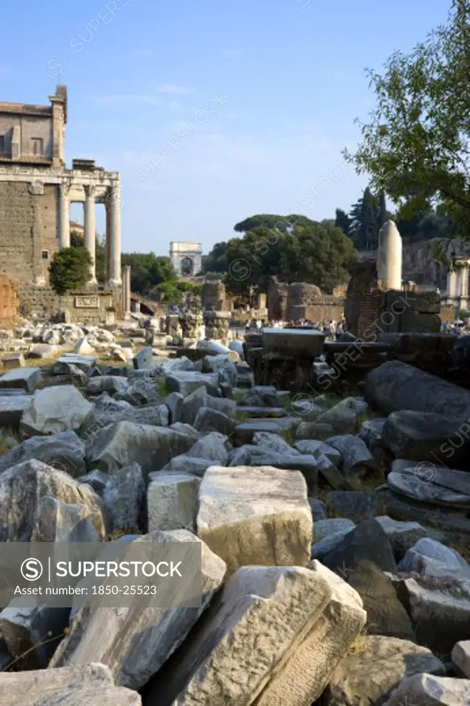 Italy, Lazio, Rome, Fallen Remains Of Buildings In The Forum With The Temple Of Antoninus And Faustina On The Left And The Arch Of Titus In The Distance
