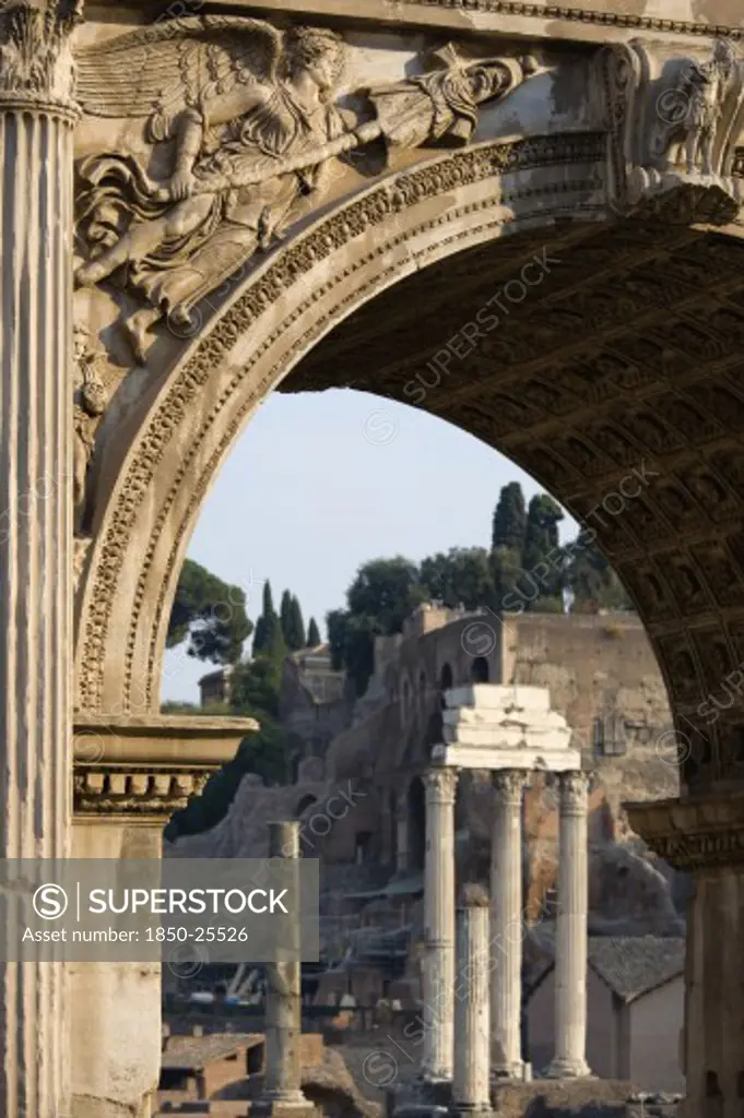 Italy, Lazio, Rome, The Three Corinthian Columns Of The Temple Of Castor And Pollux And The Walls Of The Palatine Seen Through The Arch Of Septimius Severus In The Forum