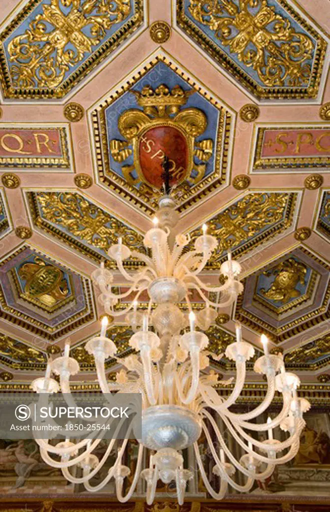 Italy, Lazio, Rome, Capitoline Museum Palazzo Dei Conservatore Chandelier Hanging From The Ceiling In The Palace With Spqr Visible On The Ornately Decorated Ceiling
