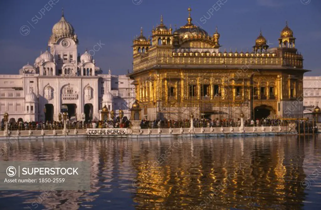 India, Punjab, Amritsar, The Golden Temple Reflected In Rippled Surface Of Pool.