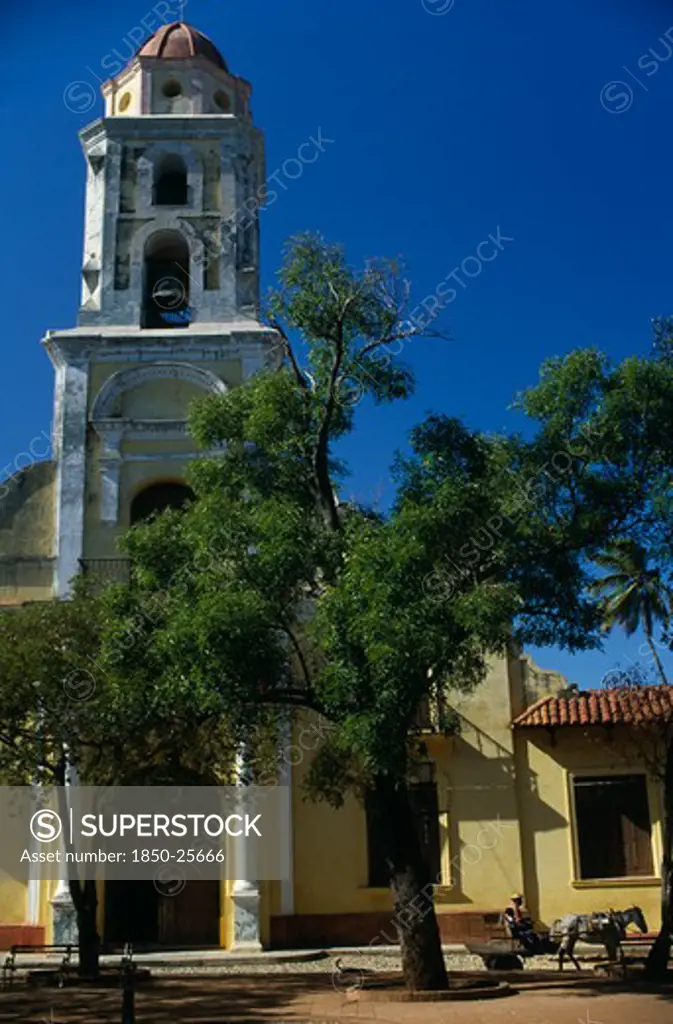 Cuba, Trinidad De Cuba, 'Exterior Of The Former Church Now A Museum Of The Revolutionary Struggle. National Museum Of The Struggle Against The Bandits, Previously A Church And Convent Of San Francisco. Passing Horse Drawn Cart, Tree In Foreground.'