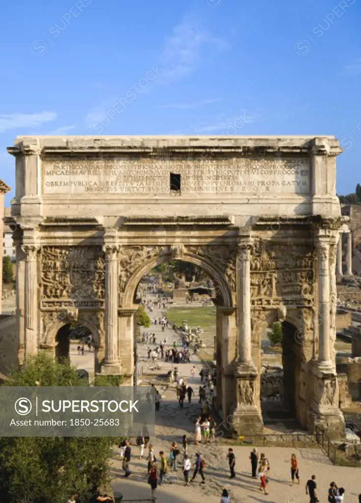 Italy, Lazio, Rome, Tourists Walking Around The Triumphal Arch Of Septimus Severus In The Forum