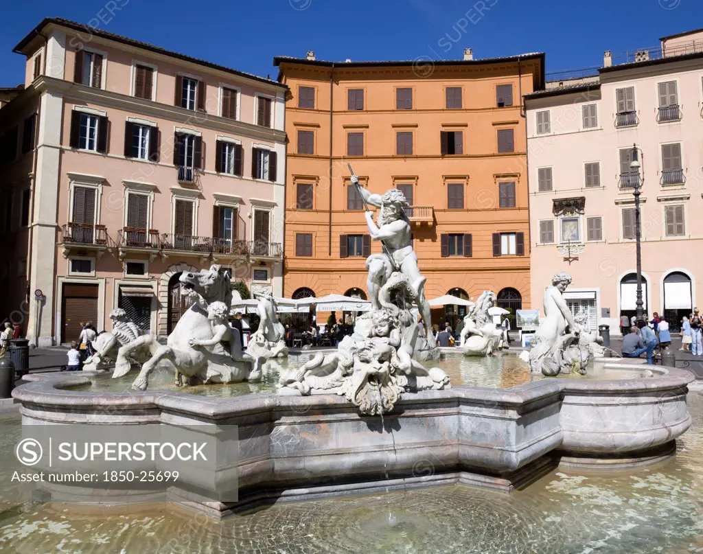 Italy, Lazio, Rome, The Fountain Of Neptune Or Fontana Del Nettuno In The Piazza Navona With Tourists Walking Past Restaurants Beyond