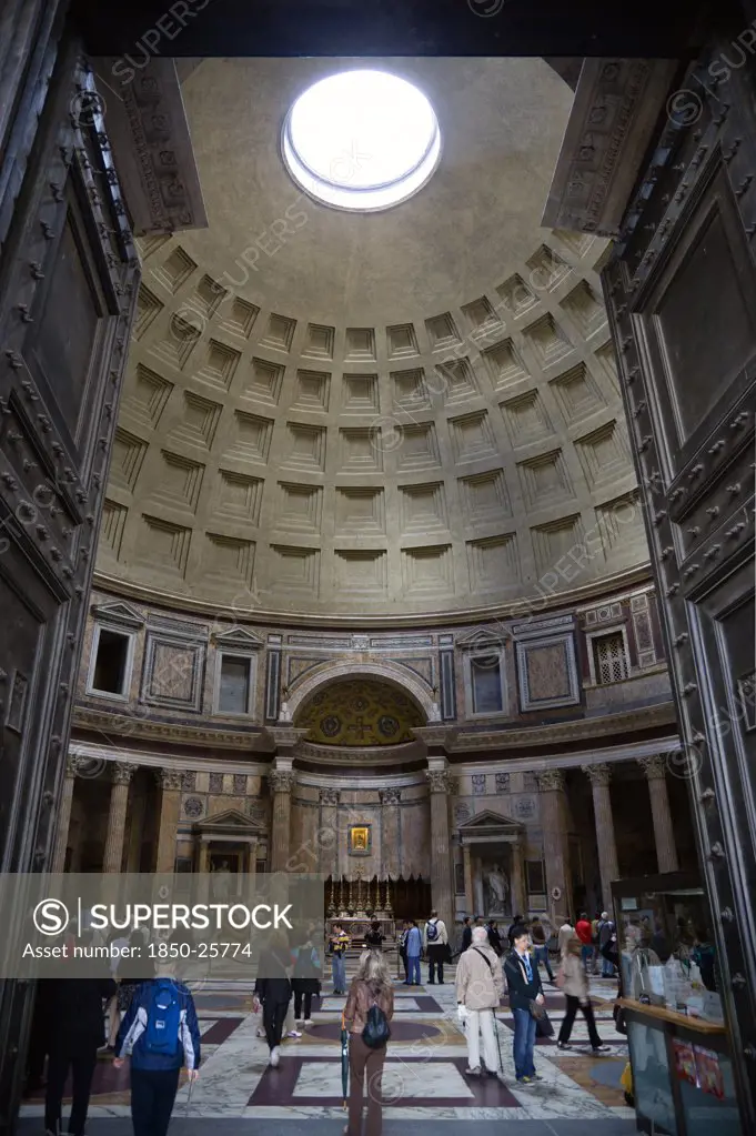 Italy, Lazio, Rome, The Interior Of The Pantheon Showing The Oculus Central Opening And The Coffering Construction Of The Dome With Tourists Walking On The Patterned Marble Flooring
