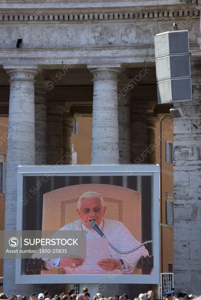 Italy, Lazio, Rome, Vatican City Pilgrims In St Peter'S Square For The Wednesday Papal Audience In Front Of The Basilica Watching Pope Benedict Xvi Joseph Alois Radzinger With A Cardinal On A Large Video Tv Monitor Display